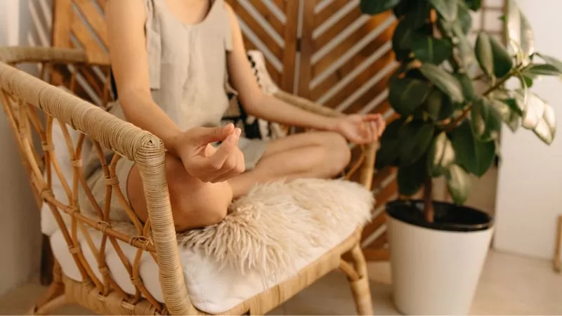 A Person in Yoga Pose on a Wicker Chair