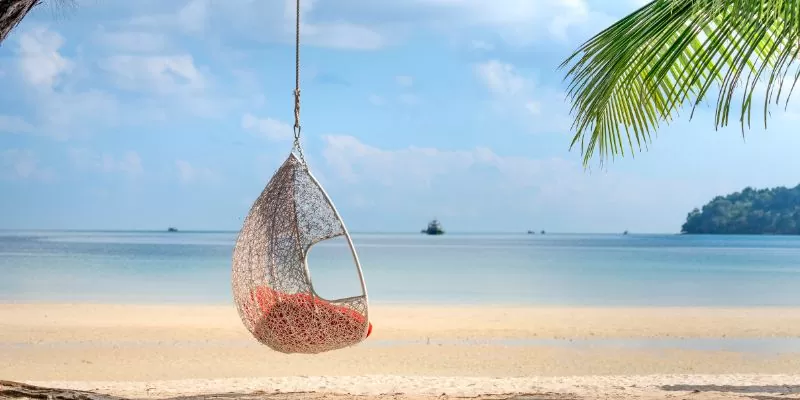 Wicker hanging egg chair on picturesque seaside
